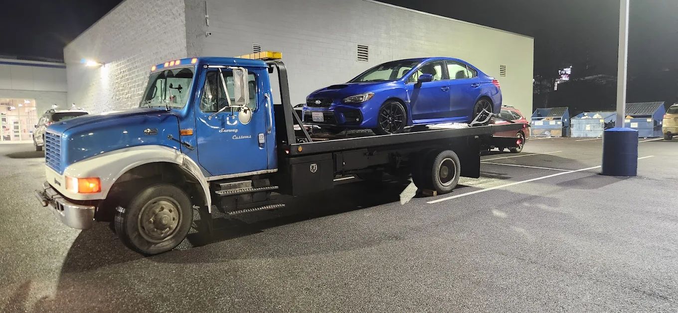 Blue Subaru loaded on the flatbed at night